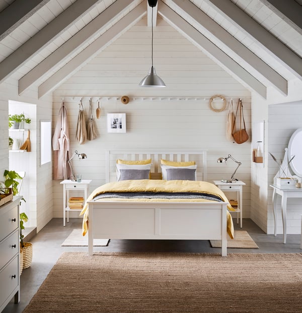 Bright room with white HEMNES bed. On the bed a yellow duvet cover and beside it two white nightstands.