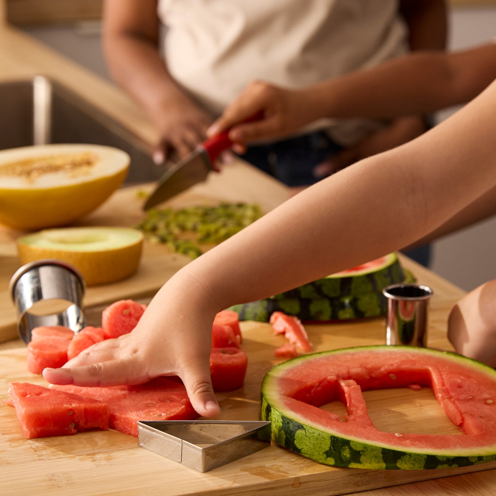 Haur baten eskuen lehen planoa meloia eta sandia LÄTTBAKAD ore-moztekoarekin zatitzen.