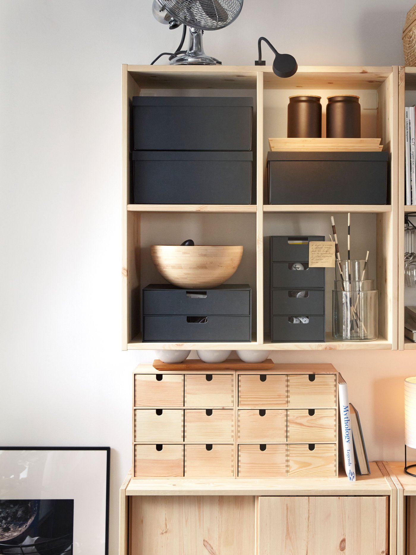 Nad szafkami IVAR z przesuwnymi drzwiami zamontowane są dwie sosnowe półki ścienne IVAR, które mieszczą czarne pojemniki i inne przedmioty. 