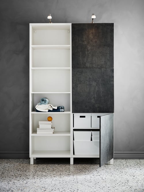 Front view of bedroom storage cabinet with plastic storage boxes with lids, LED cabinet lighting and various belongings.