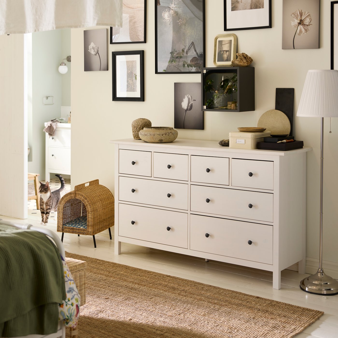 A white stain HEMNES chest with 8 drawers with various objects on top and an UTSÅDD cat house on legs beside it.