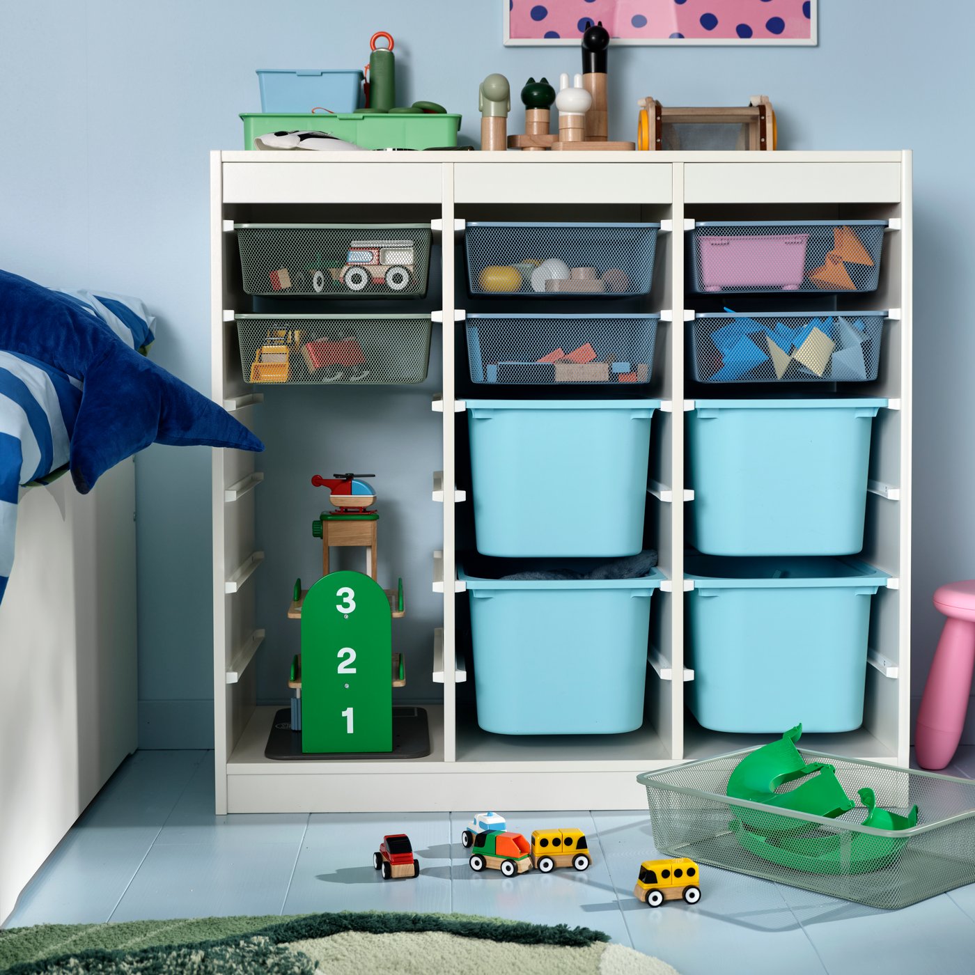 A child’s room with TROFAST storage and blue TROFAST boxes, holding a LILLABO garage and LILLABO vehicle set of four.