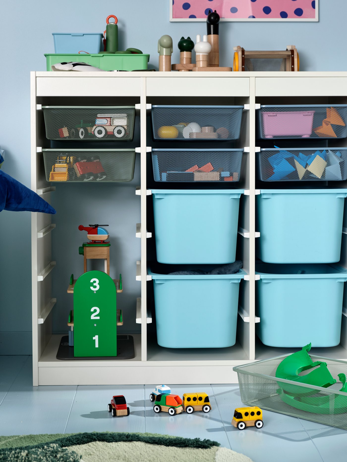 A child’s room with TROFAST storage and blue TROFAST boxes, holding a LILLABO garage and LILLABO vehicle set of four.