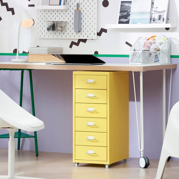 Gele ladekast onder een houten bureau