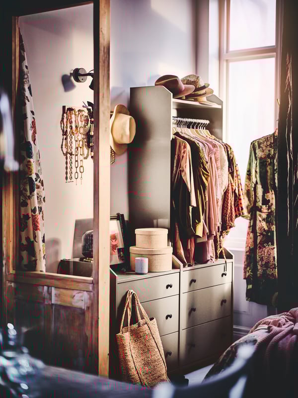 A HAUGA open wardrobe with three drawers with clothes on hangers, and a HAUGA chest with three storage boxes to the side.