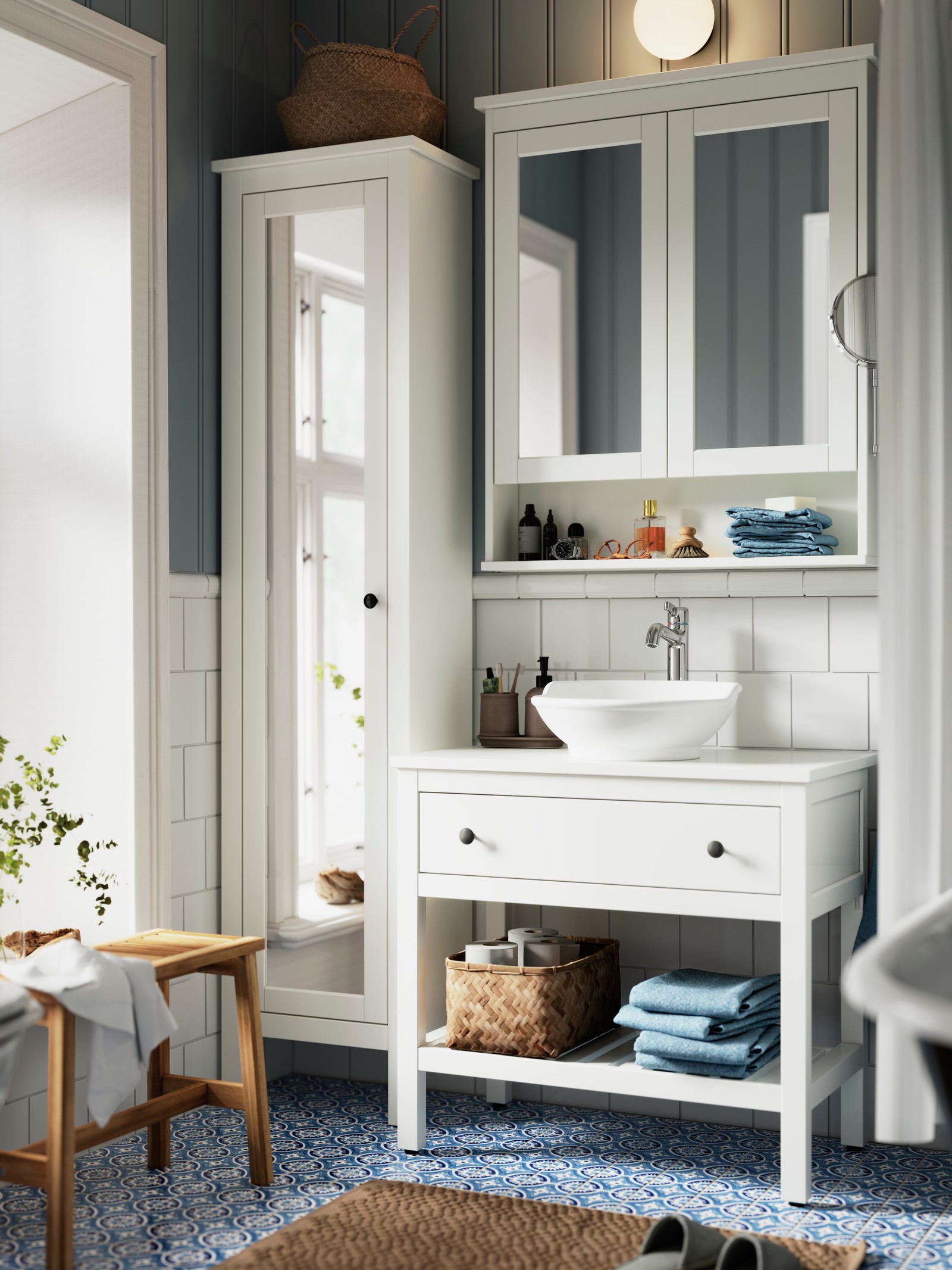A bright bathroom has a white HEMNES wash-stand, a white VÄSTERSJÖN countertop washbasin and a high cabinet with a mirror.