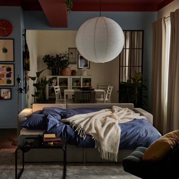 A beige/grey BÅRSLÖV 3-seat sofa-bed with chaise longue in a bright living room adorned with plants.