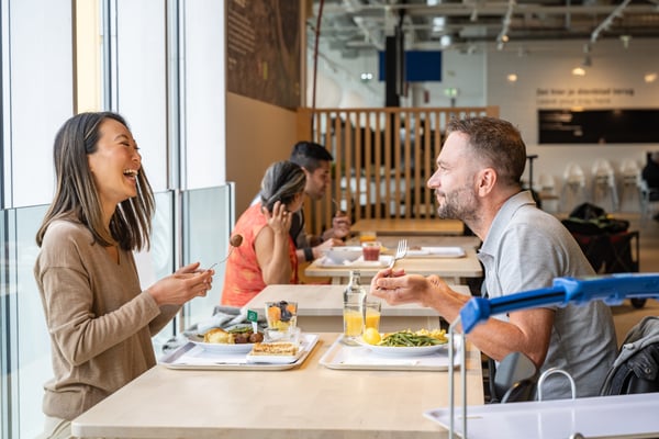 A couple enjoys a warm meal at the Swedish IKEA restaurant. Get 50% off IKEA Family breakfast and hot main courses every Friday until August 30th, 2024.