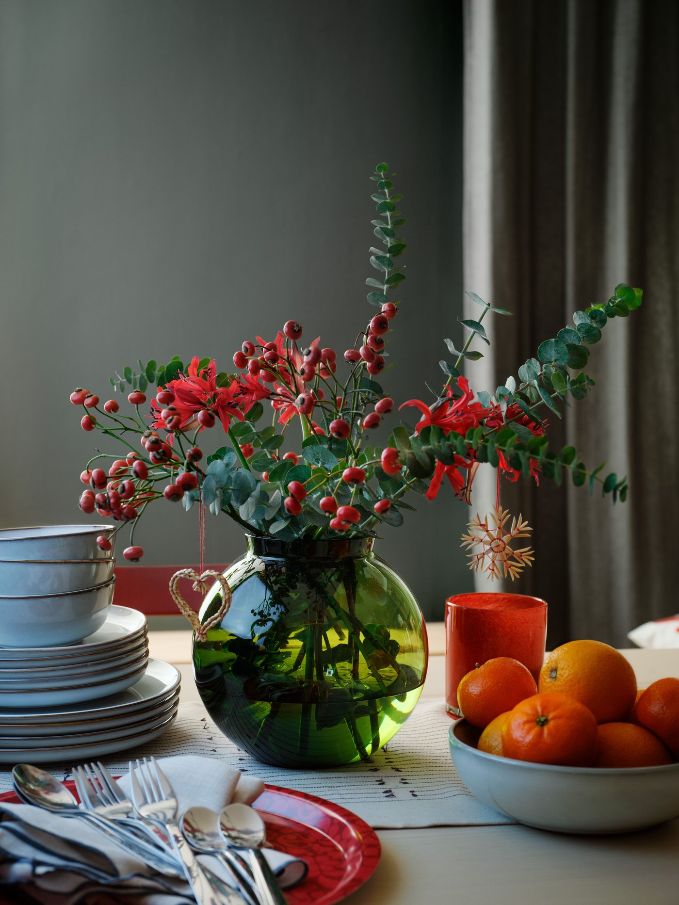 un vase vert avec des fleurs rouges d'automne