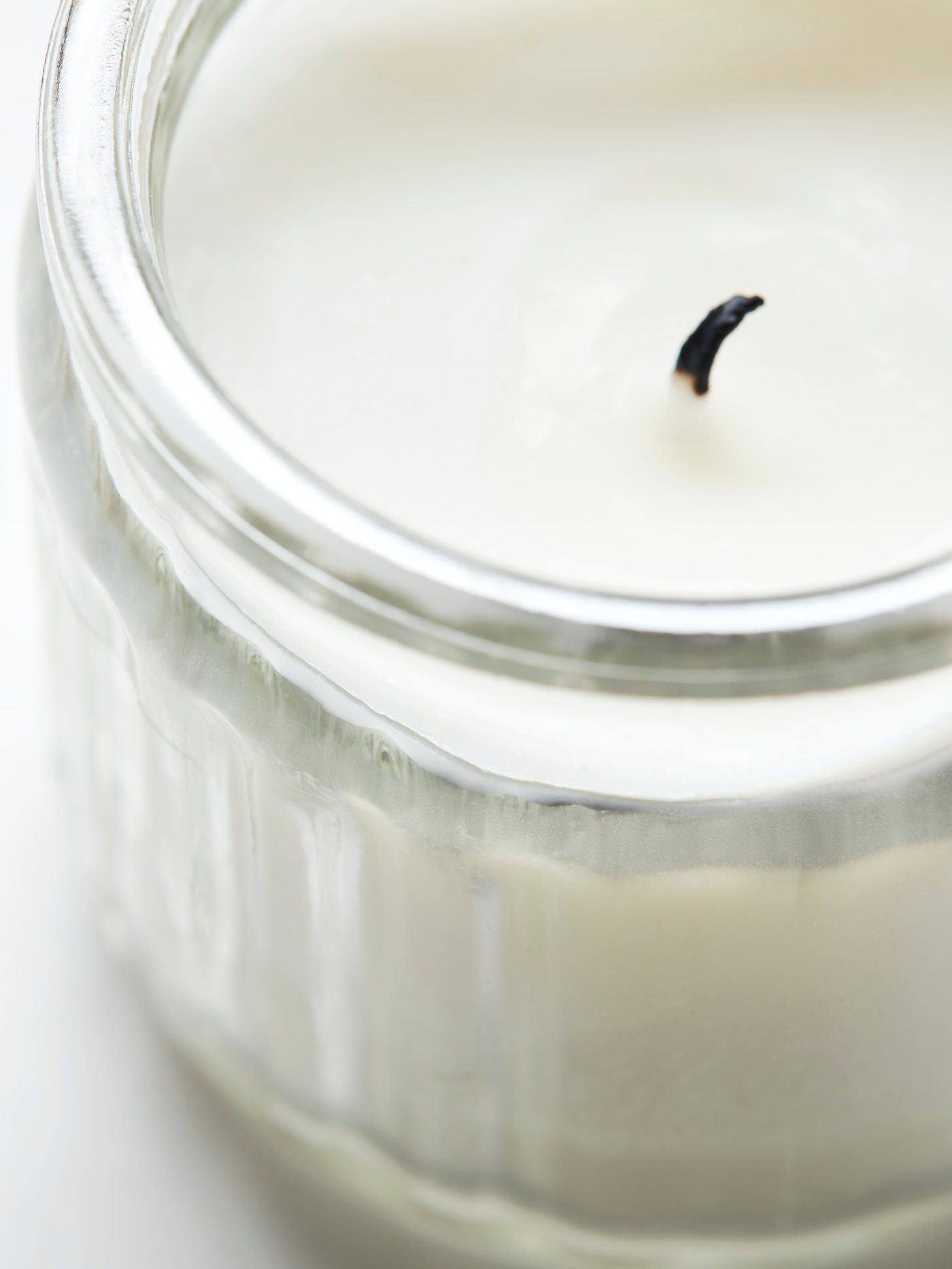 A close-up top view of an ADLAD scented candle in glass. Part of a collage of images of the candle and Scandinavian wood.