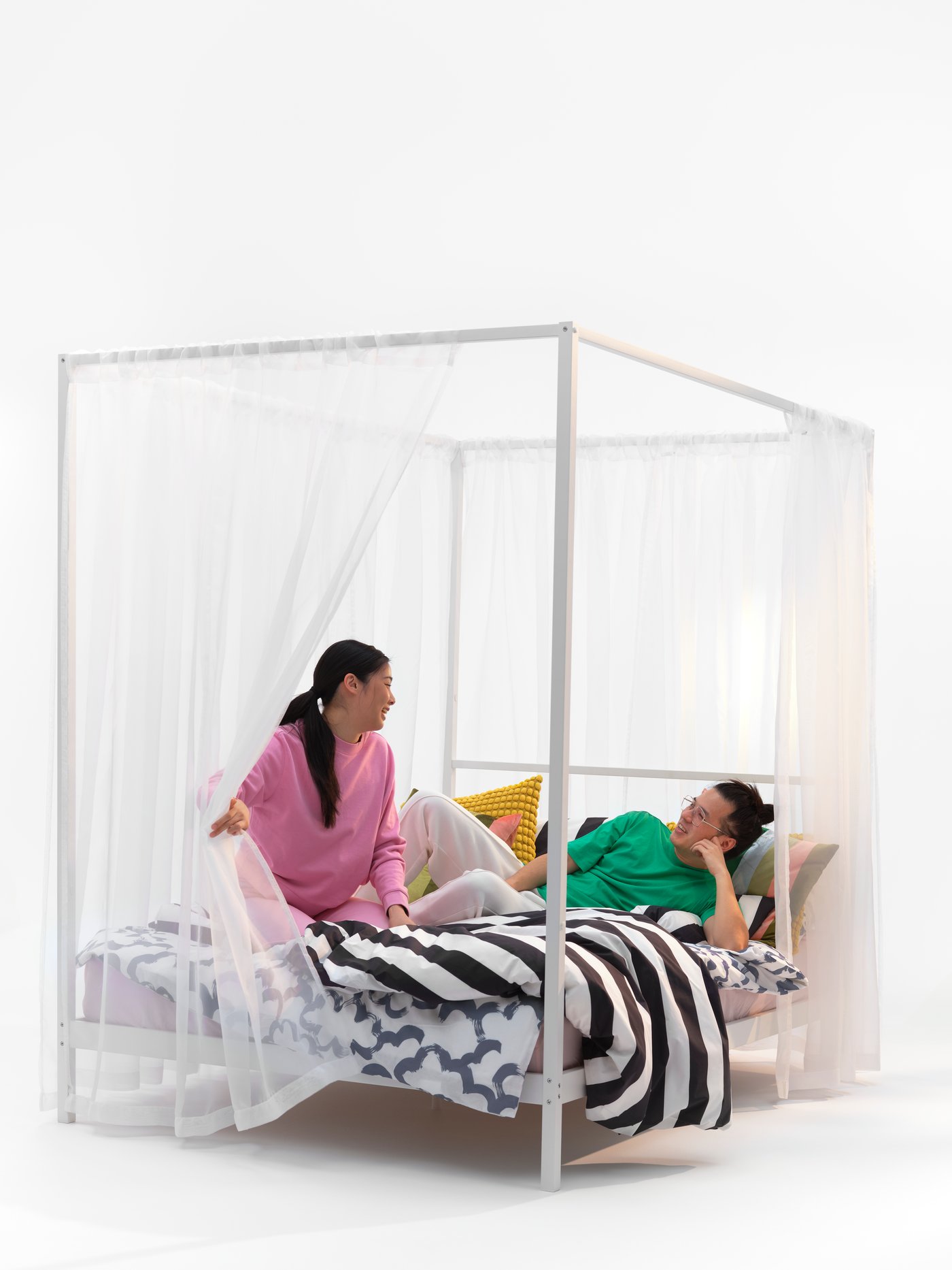 VITARNA four post bed in the bedroom with a couple on top. 