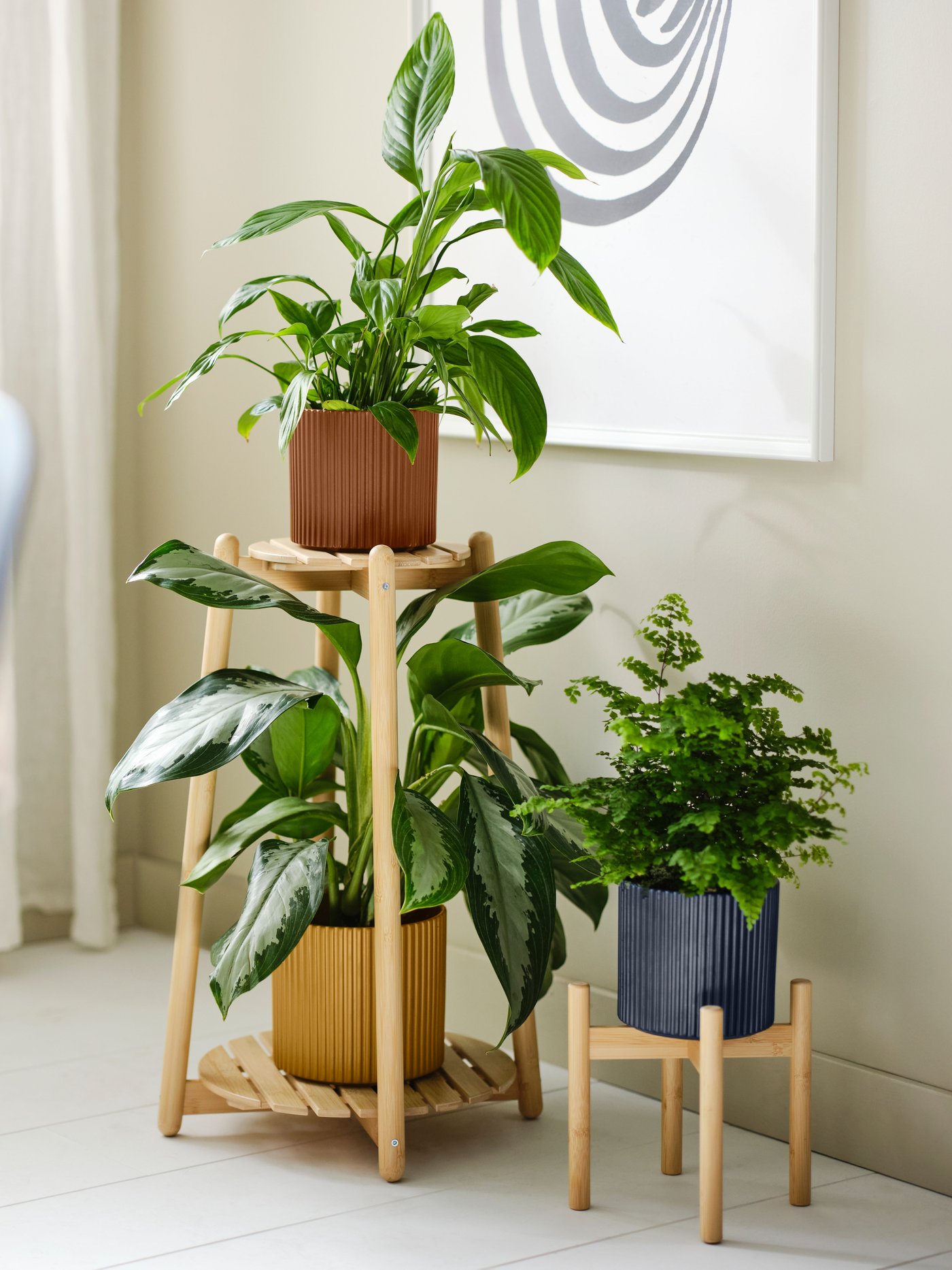 Due portavasi in bambù DAKSJUS appoggiati a una parete con una cornice