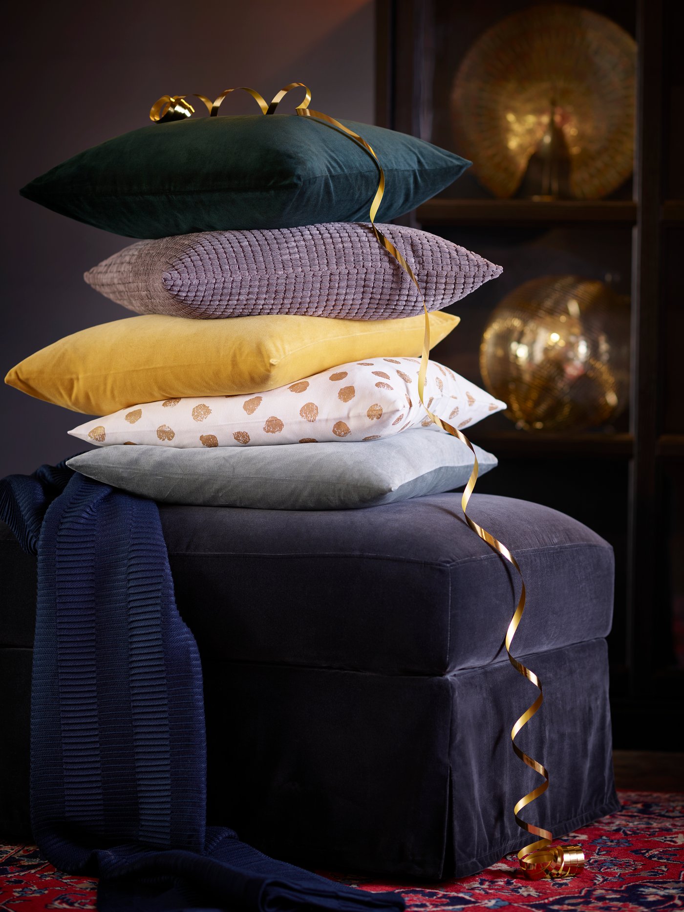Some cushions stacked on a dark grey FÄRLÖV footstool.