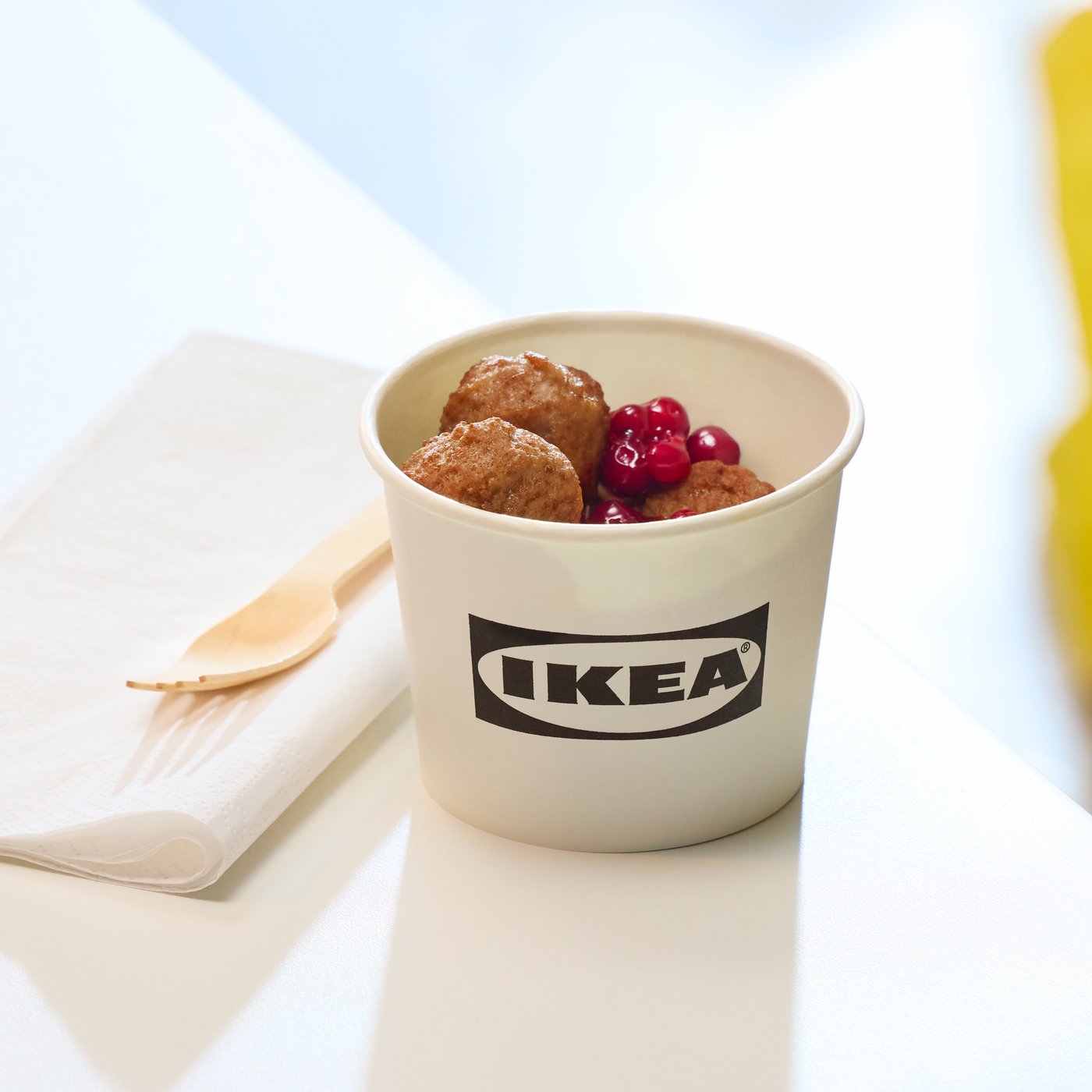a serving of meatballs in a paper bowl, with a napkin and a fork next to it