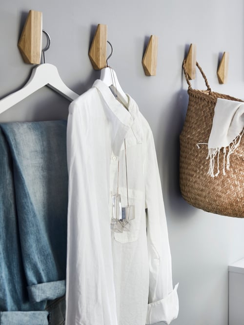 SKUGGIS bamboo hooks have BUMERANG hangers with a pair of faded jeans, a white blouse and a basket hanging from them.