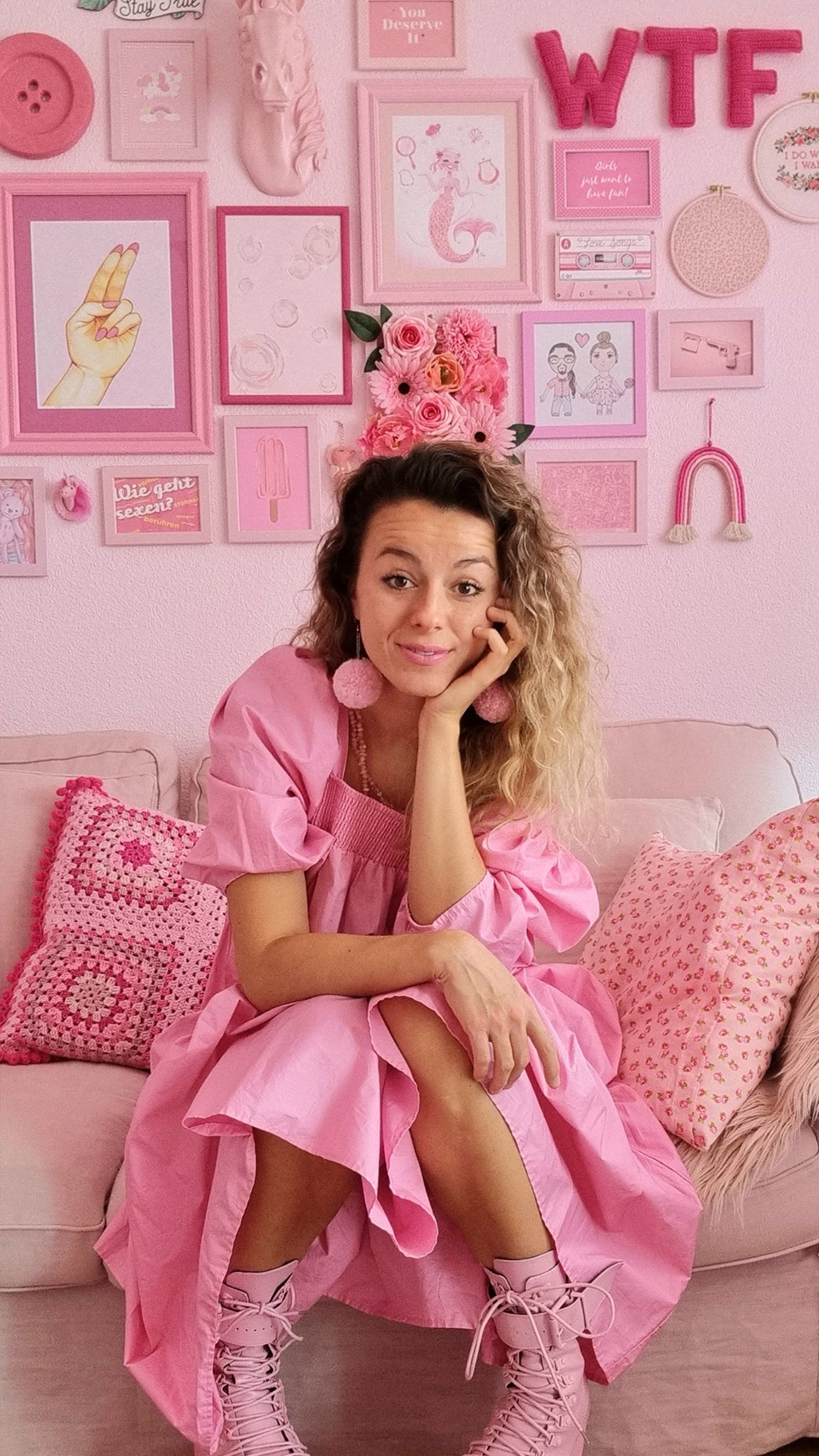 Yasmin zit voor haar roze geverfde gallery wall in de zetel.