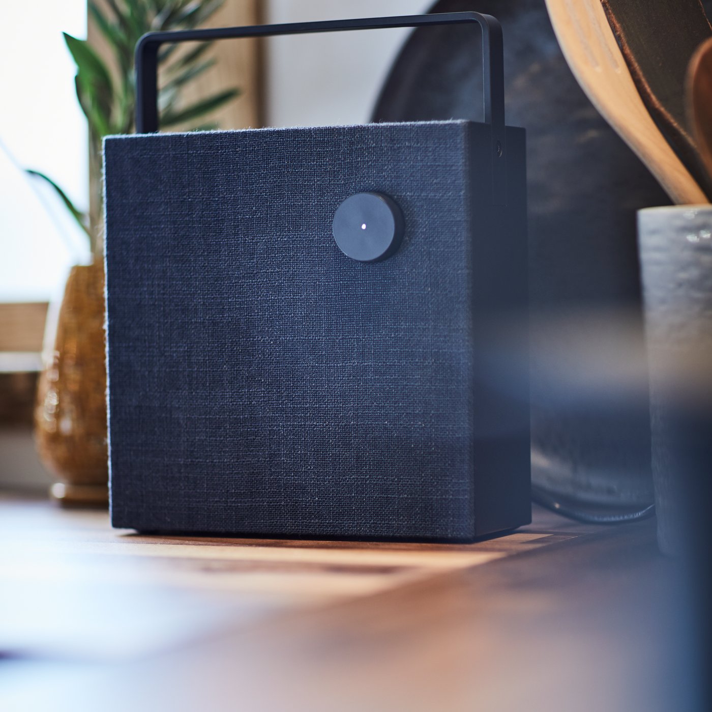 A black ENEBY Bluetooth speaker on a wooden kitchen worktop.