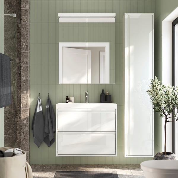 White ÄNGSJÖN vanity and high cabinet in a green bathroom. Square LETTAN mirror above 