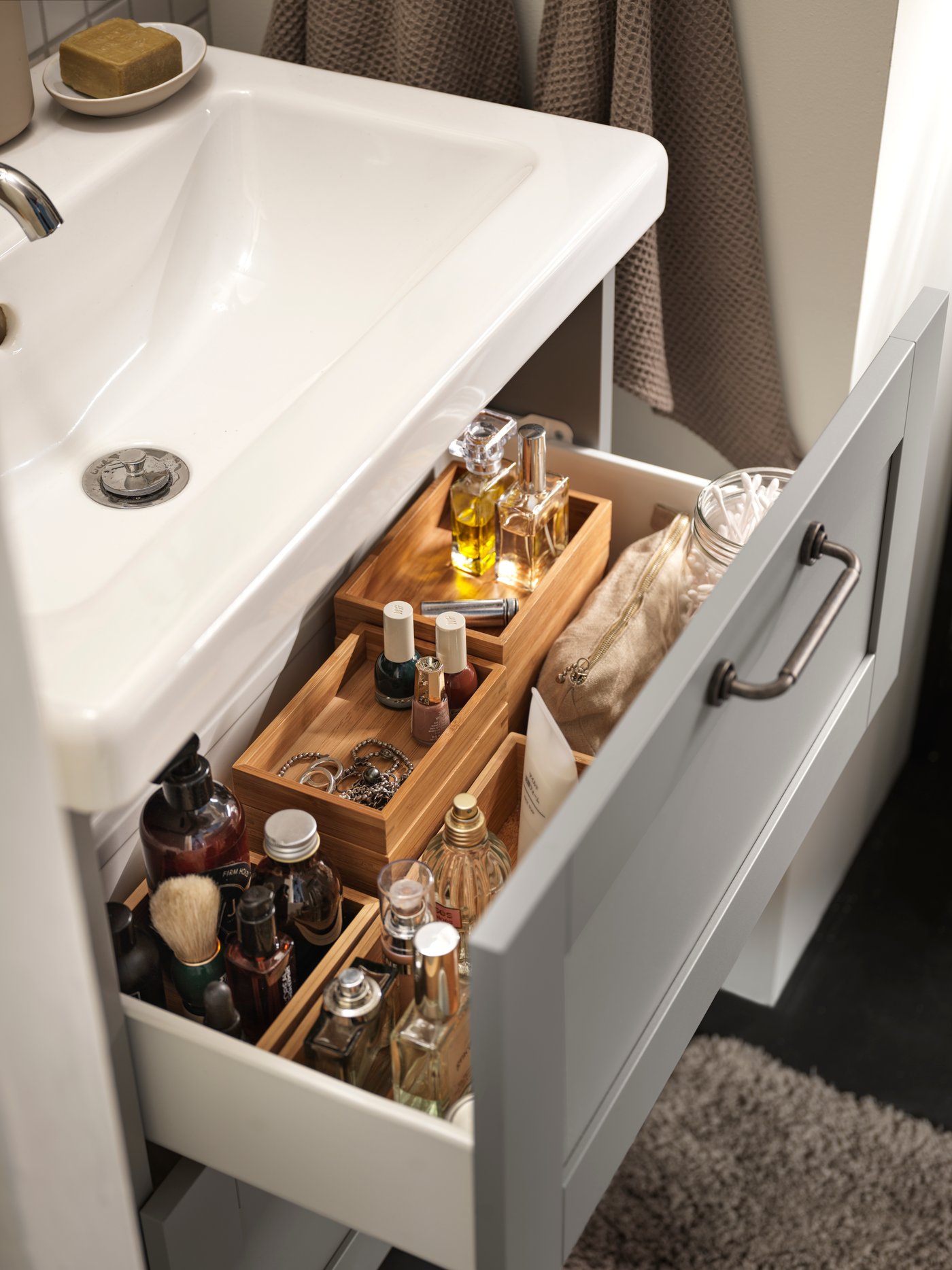 Cuarto de baño con un juego de baño beige de 4 piezas de bambú y múltiples bandejas beige dentro de un lavabo con 2 cajones.