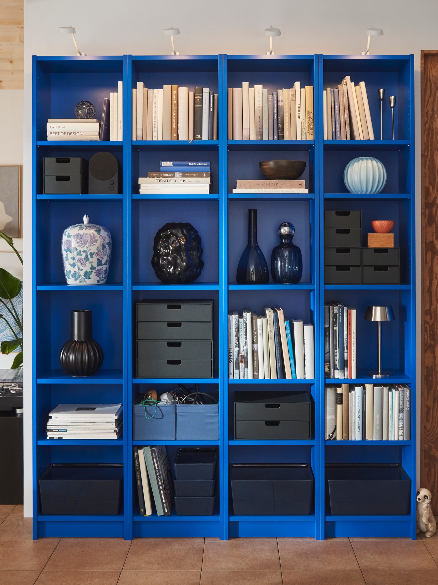 Soggiorno con una grande libreria BILLY blu piena di libri, scatole e oggetti decorativi.