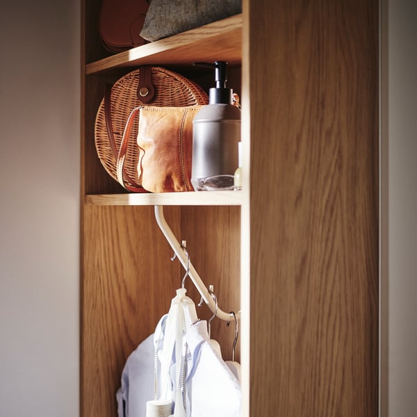 Close-up of the PAX end unit with some clothes hanging and different accessories displayed on the shelves.