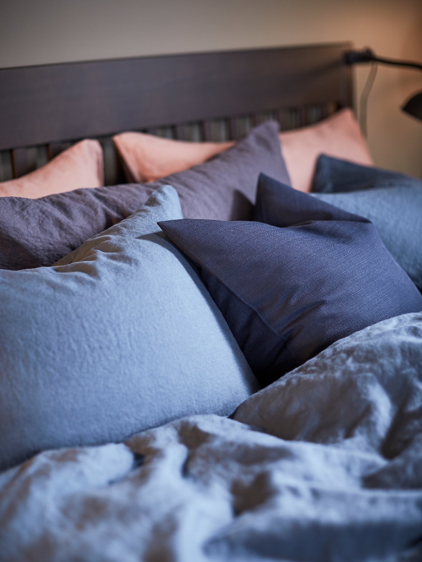 A close-up of an IDANÄS bedframe with a PUDERVIVA dark blue quilt cover and pillowcases.