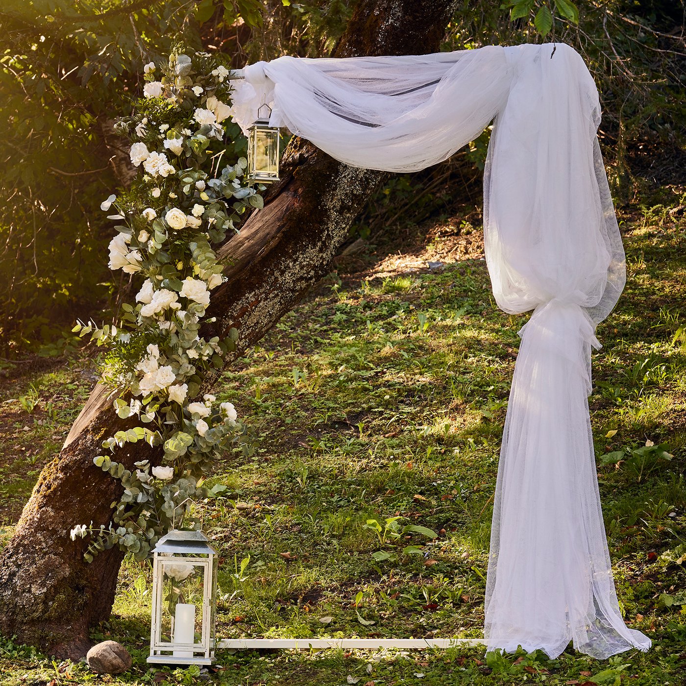 Ett egengjort fotobås med en stor fotoram dekorerad med LILL tyllgardin och SMYCKA blommor står i naturen.