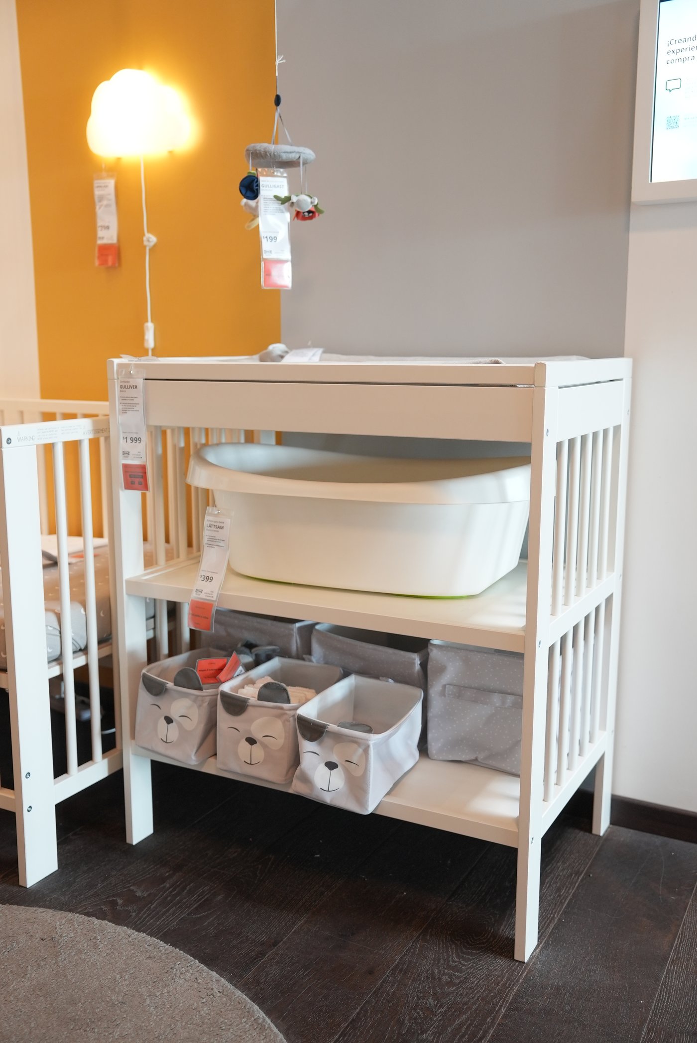 Un mudador GULLIVER con una baññera para bebé en una de sus repisas.
