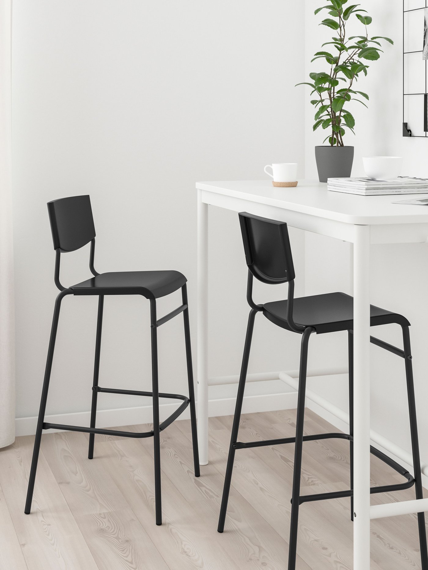 Dos sillas de bar STIG negras frente a una mesa alta.