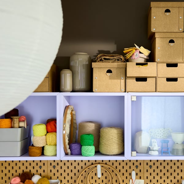 Close-up of an EKET shelving unit in pale lilac, filled with colourful yarn, crafting supplies and multi-sized storage boxes.
