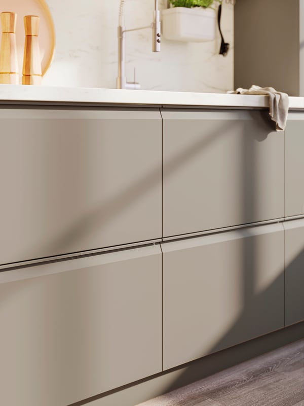 Close up of UPPLÖV drawer fronts in matte dark beige with a white worktop