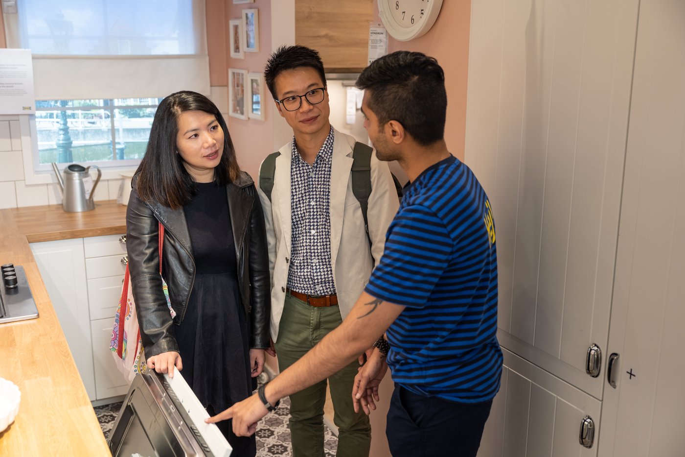 Two customers approaching IKEA co-worker to discuss return policy and claims