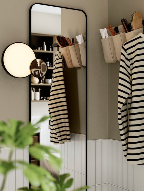 Bedroom featuring a rectangular LINDBYN mirror, a black KABOMBA LED wall lamp with mirror and a beige NEREBY container.
