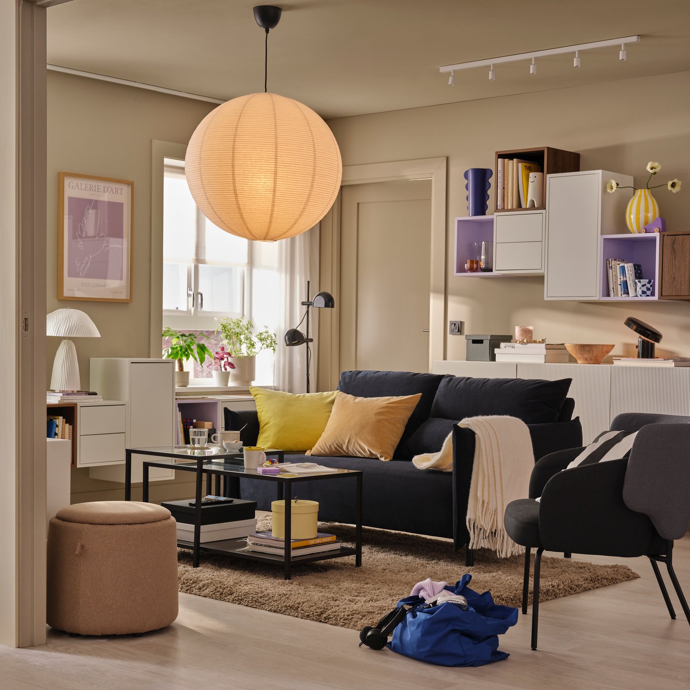 A living room featuring a black-blue MANNARP two-seat sofa set against light walls with a decorative cabinet arrangement.