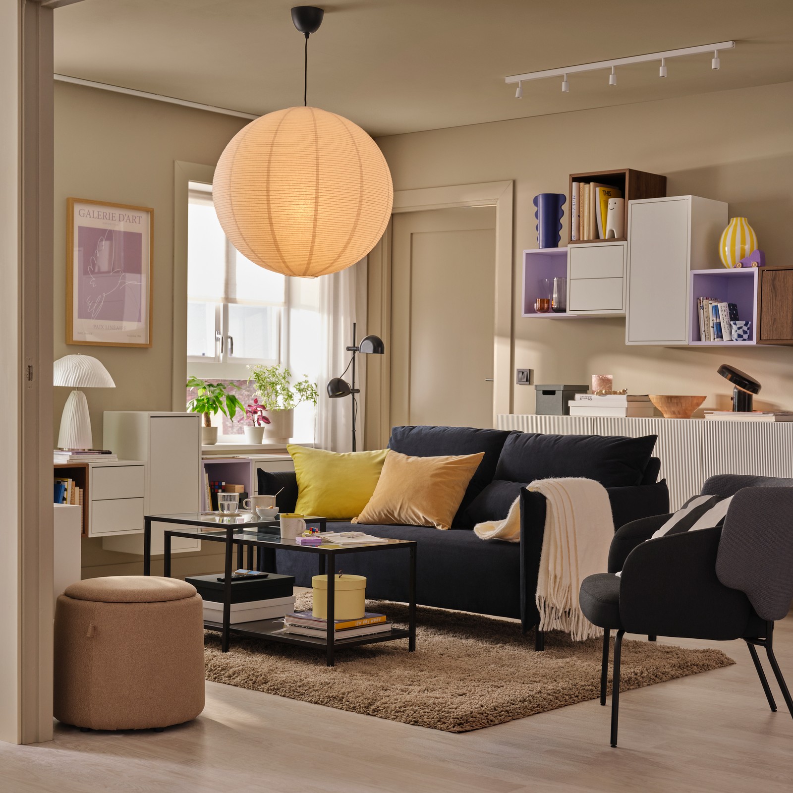 A living room featuring a black-blue MANNARP two-seat sofa set against light walls with a decorative cabinet arrangement.