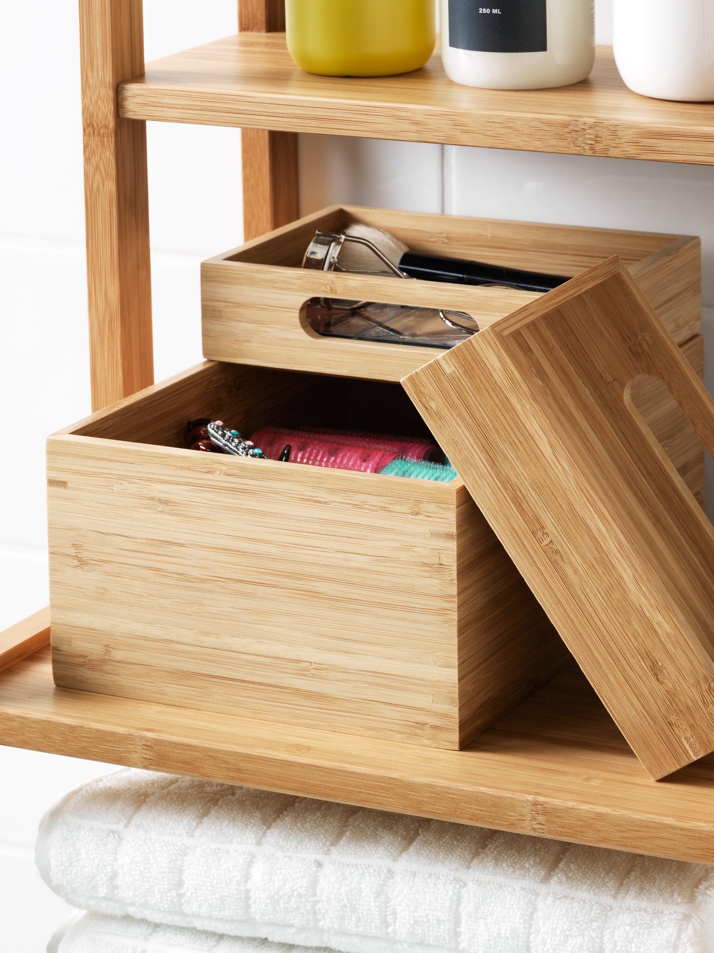 Drewniane pudełka DRAGAN stoją na bambusowym regale w łazience. 