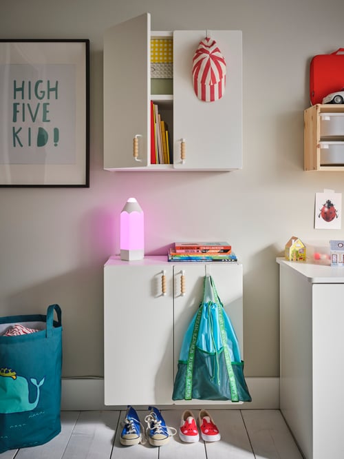 Bathroom area featuring a wall cabinet with one door open mounted above another wall cabinet with a lit table lamp.