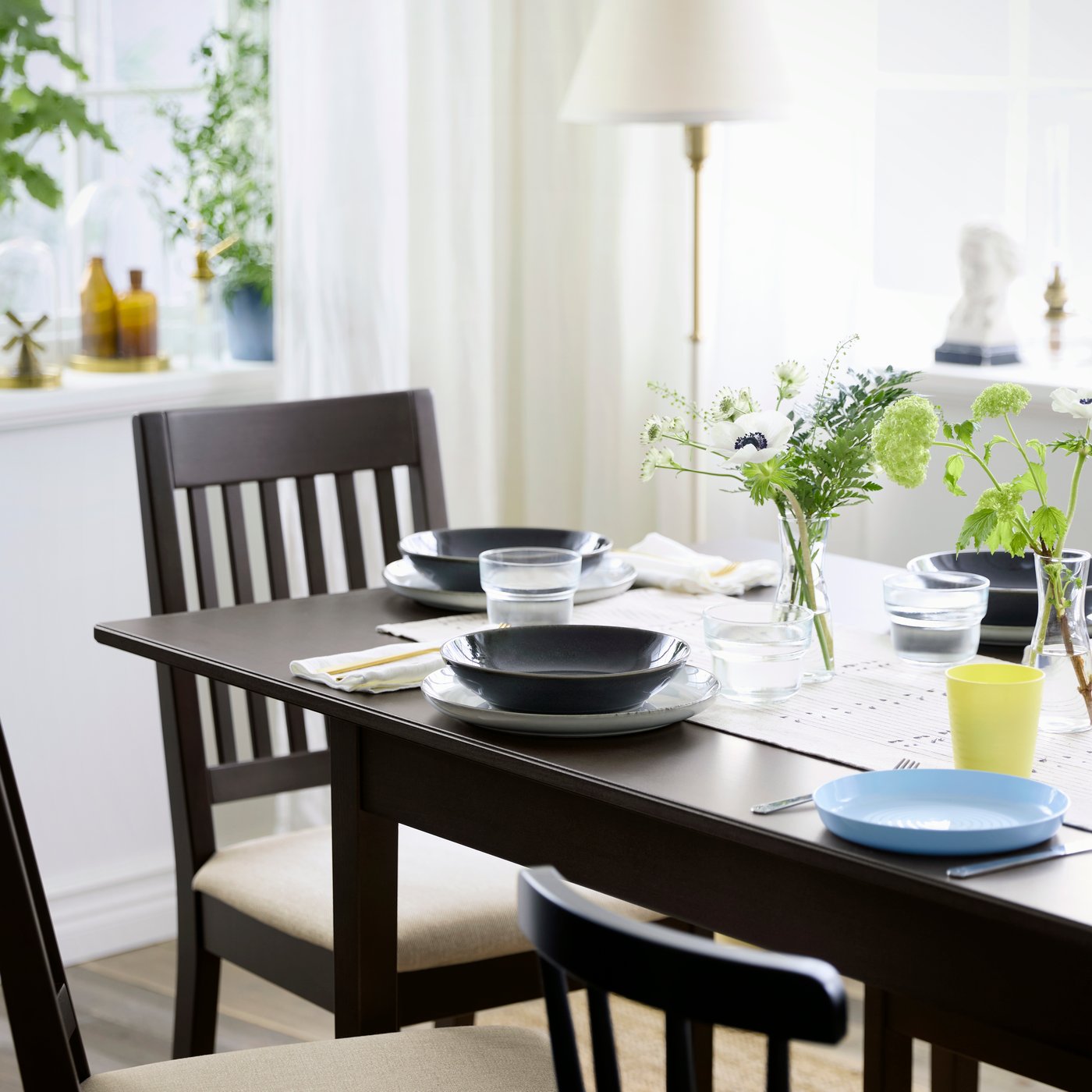 A modern dining room with NÄSINGE table and chairs in dark brown, with decorative plants.