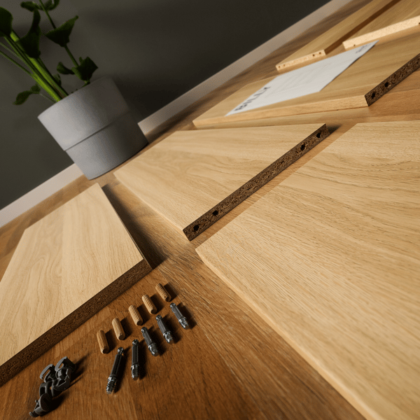 Panels, screws, and assembly instructions for a Billy bookcase are neatly arranged on the floor, ready for assembly.