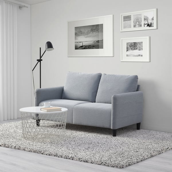 Un sofá ANGERSBY gris de dos puestos en una sala sobre un tapete IKEA.