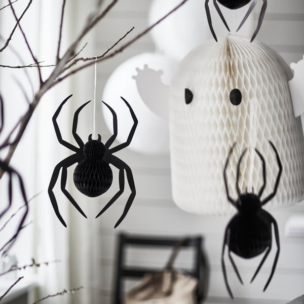 Some KUSTFYR hanging decorations, one shaped like a ghost and two shaped like spiders, are placed in a white room.