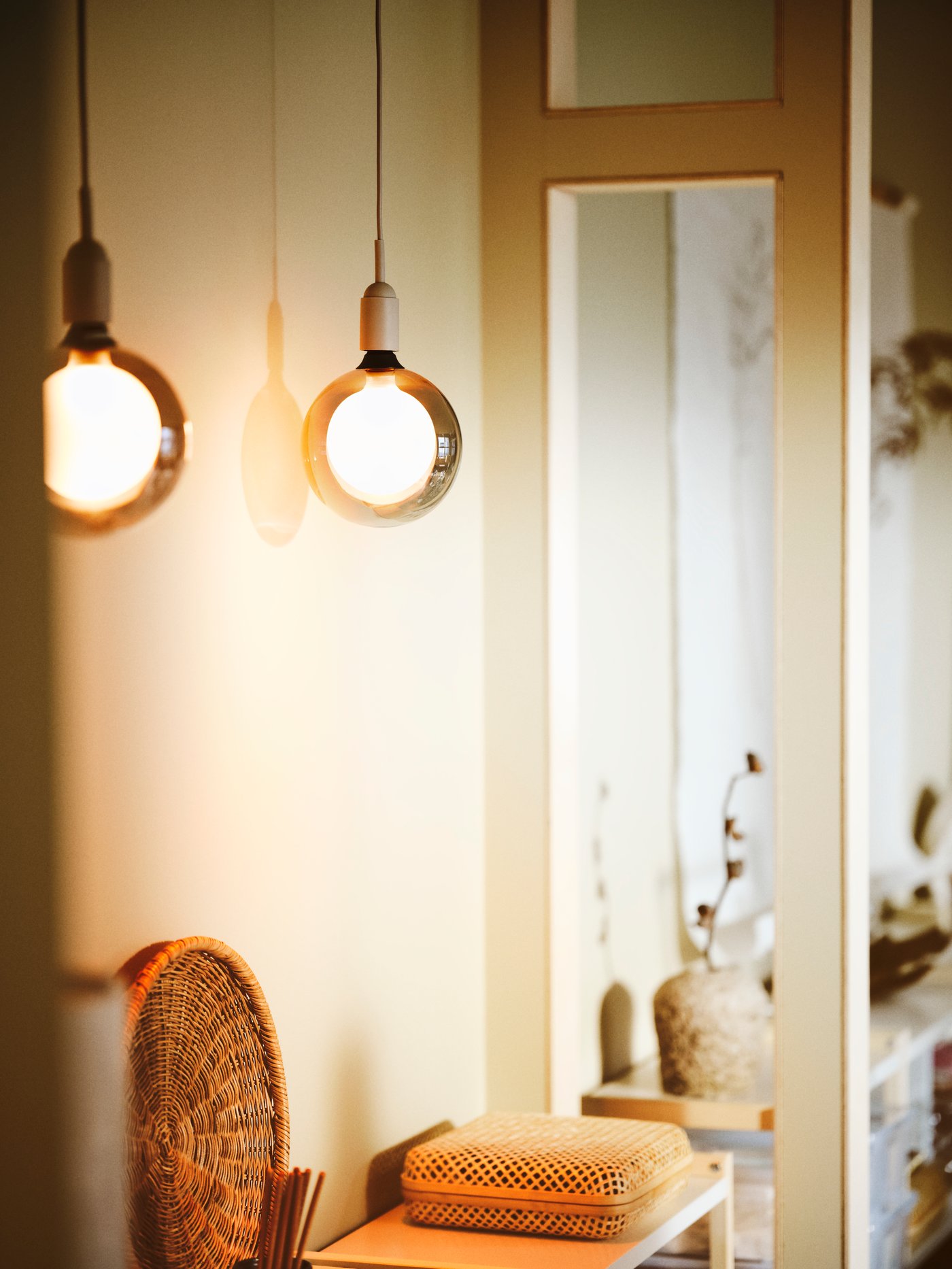 A room with two MOLNART LED bulbs placed in cord sets, hung on the ceiling, a storage basket, a table, vases, flowers.