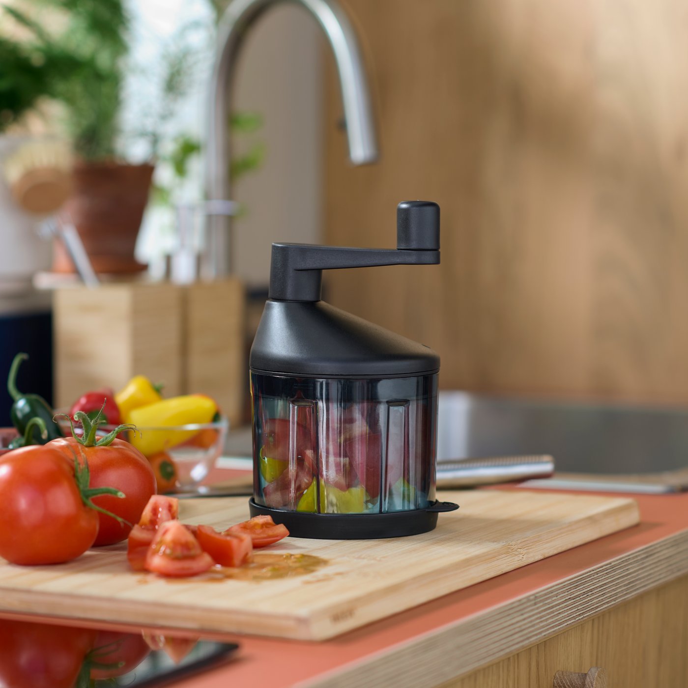 赤いトマトと黄色のパプリカの入ったSTENSNULTRA/ステンスヌルトラ ベジタブルチョッパーが、木製のまな板の上に置いてある。