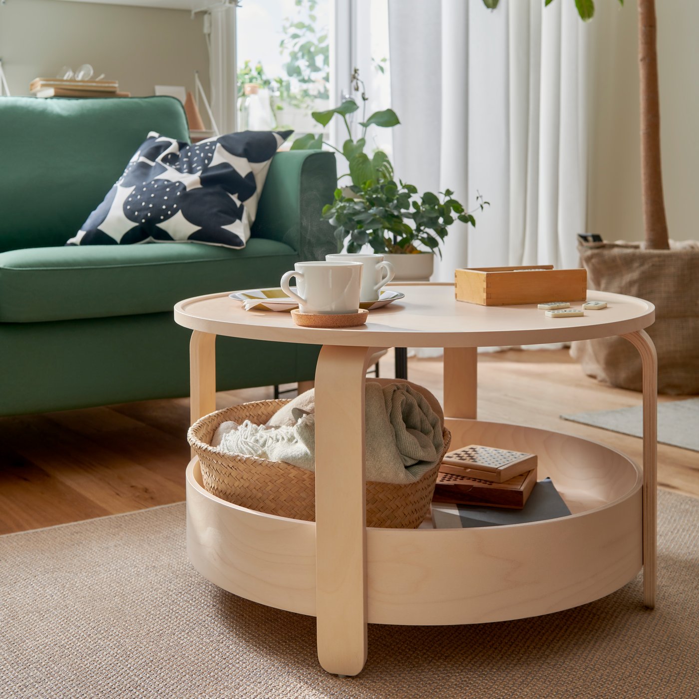 A light wooden BORGEBY coffee table in the living room in front of a green sofa.