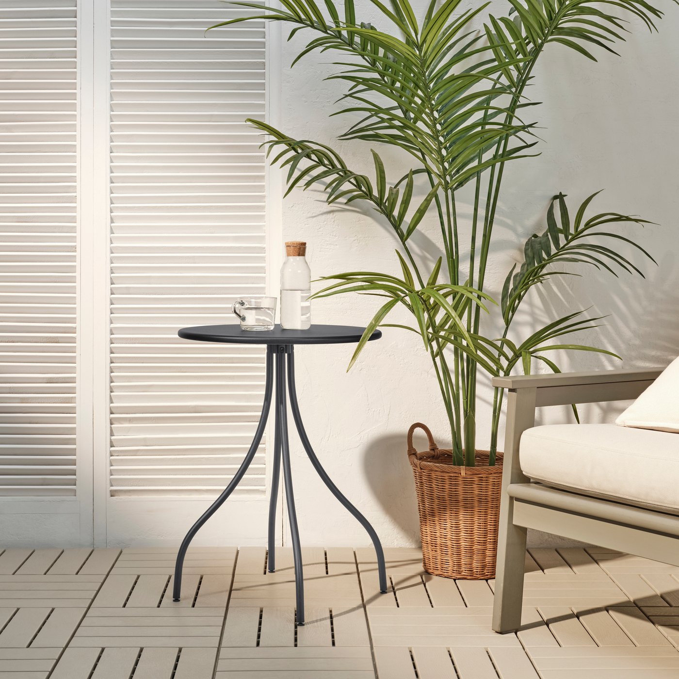 Mesa auxiliar TÅNEBRO para interior y exterior en color antracita, colocada en un espacio al aire libre.