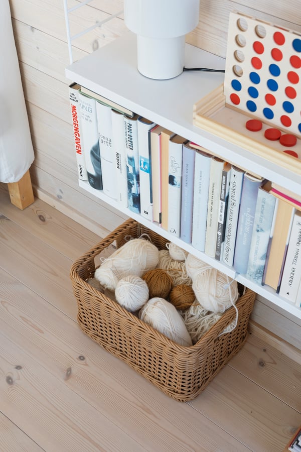 Canasta BEKNA de ratán plástico utilizada para almacenamiento en un dormitorio.