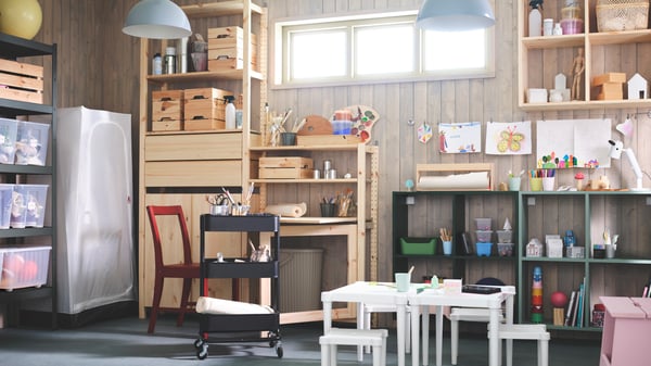 A large IVAR storage combination in natural pine and dark green, filled with boxes, hobby accessories and kid’s art stuff.