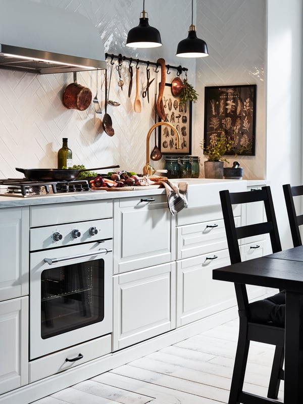 Una cucina di colore bianco con lavello HAVSEN. Alla parete, una cornice con poster KNOPPÄNG.