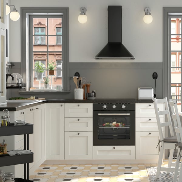 A black and white traditional-style kitchen with a white NORDVIKEN dining table surrounded by three chairs and a pine bench.