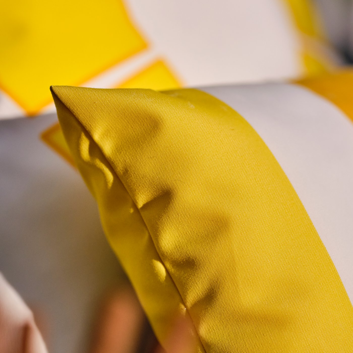 Una funda de cojín GULLBERGSÖ con rayas amarillas/blancas para exteriores e interiores